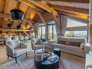Experience luxury mountain living in this stunning chalet featuring a spacious living area with a cozy fireplace and large windows offering breathtaking views.