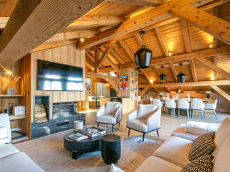 Experience luxurious mountain living in this stunning chalet, featuring a grand living area with a modern fireplace and a large flat-screen TV.