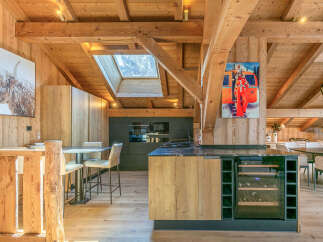 Experience luxury mountain living in this stunning chalet featuring a modern kitchen with a wine fridge and sleek cabinetry.