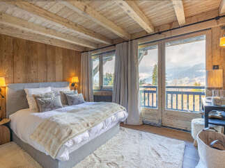 Experience rustic luxury in this charming mountain bedroom, featuring a cozy king-sized bed adorned with plush pillows and a warm, textured throw.