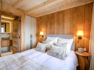 Experience rustic luxury in this charming bedroom featuring warm wood paneling and exposed beams.