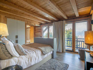 Experience luxurious mountain living in this stunning bedroom featuring a cozy bed with plush pillows and a warm, inviting ambiance.