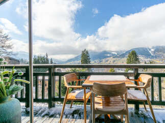 Enjoy breathtaking mountain views from this charming balcony, complete with a rustic wooden table and chairs.
