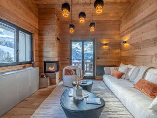 Experience luxury mountain living in this stunning chalet, featuring a cozy fireplace and breathtaking views from the large windows.