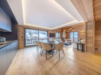 Experience luxurious mountain living in this stunning chalet, featuring a modern open-plan kitchen and dining area with breathtaking views of the snowy landscape.