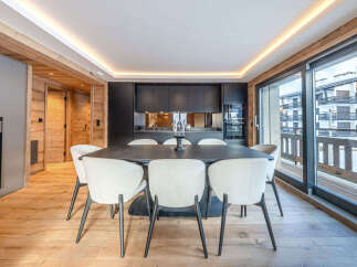 Experience modern alpine living in this stunning dining area, featuring a sleek dark wood table surrounded by plush, cream-colored chairs.