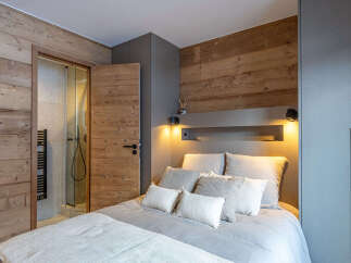 Experience cozy mountain living in this charming bedroom featuring rustic wood paneling and a luxurious king-sized bed.