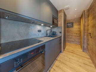 Experience modern living in this sleek kitchen featuring dark cabinetry and a stone-effect backsplash.