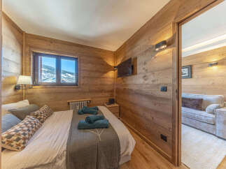 Experience cozy mountain living in this charming bedroom featuring warm wood paneling and a comfortable bed adorned with plush pillows and soft blankets.