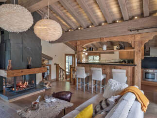 Experience luxury mountain living in this stunning chalet, featuring a modern stone fireplace and a fully equipped bar area perfect for entertaining.