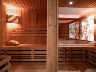 Experience ultimate relaxation in this luxurious wooden sauna, featuring multi-level seating and ambient lighting.