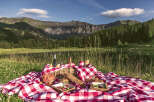 Experience the ultimate outdoor living with a picturesque picnic setup overlooking a serene lake and majestic mountains.