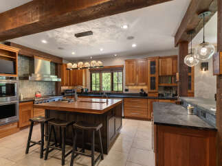 Experience rustic elegance in this stunning mountain kitchen, featuring rich wood cabinetry and exposed beams.