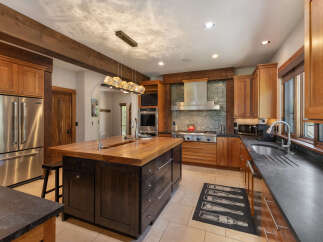 Experience luxury in this stunning kitchen featuring a large wooden island with a built-in sink, perfect for meal preparation and entertaining.