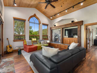 Experience rustic charm and modern comfort in this stunning living room, featuring a grand stone fireplace and a vaulted wood-paneled ceiling with a stylish fan.
