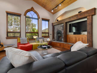 Experience luxury mountain living in this stunning living room, featuring a grand stone fireplace and a large flat-screen TV.