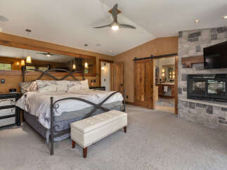Experience luxury in this master suite featuring a king-sized bed with marble-patterned bedding and a plush ottoman.