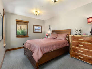 This charming bedroom features a rustic wooden bed with a salmon-colored comforter, complemented by a matching dresser with natural wood accents.