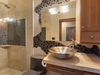 Experience luxury in this modern bathroom featuring a unique pebble tile accent wall that adds a natural, organic feel.