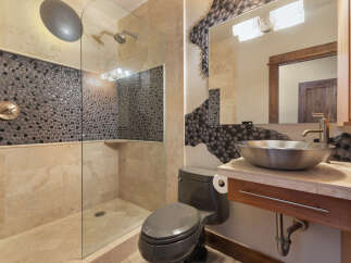 Experience luxury in this modern bathroom featuring a spacious walk-in shower with unique pebble tile accents and a sleek glass enclosure.