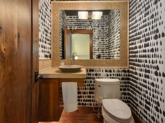 This powder room features a striking black and white abstract wallpaper that adds a bold statement to the space.