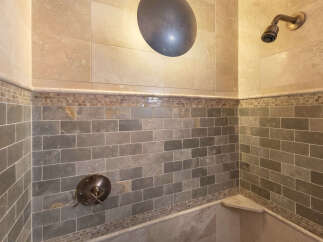 Experience luxury in this beautifully tiled shower featuring a modern rain shower head and a built-in bench.