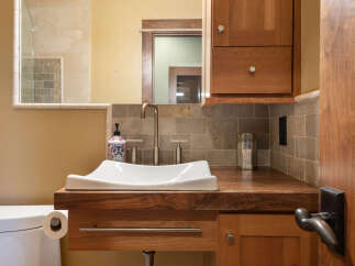 This modern bathroom features a sleek white vessel sink atop a rich walnut vanity, complemented by a brushed nickel faucet and coordinating hardware.