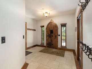 Step into this charming entryway featuring a unique arched wooden door with intricate iron hardware.