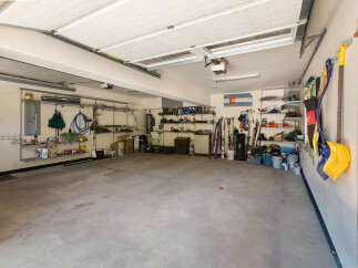 This spacious garage offers ample storage solutions with multiple shelving units and wall-mounted racks, perfect for organizing sports equipment and tools.