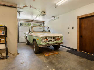This spacious garage features a classic light green and white Ford Bronco, perfect for car enthusiasts.
