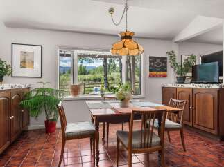 Enjoy scenic mountain views from this charming dining area, featuring a large window overlooking lush greenery and distant peaks.