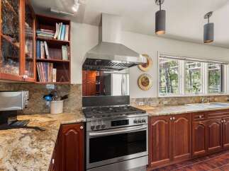 This spacious kitchen boasts beautiful granite countertops and rich cherry wood cabinetry, offering ample storage and a warm, inviting atmosphere.