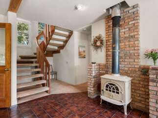 Step into this charming entryway featuring a beautiful wooden door and a carpeted staircase leading upstairs.
