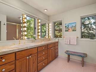 This spacious bathroom features a double vanity with marble countertops and ample storage in the wooden cabinetry.