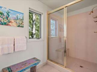 Step into this charming bathroom featuring a spacious walk-in shower with elegant pink tile and a built-in bench.