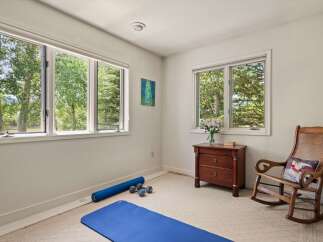 This room offers a serene space for relaxation and wellness, featuring large windows that flood the area with natural light and offer picturesque views of the surrounding trees.