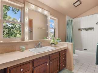 This charming bathroom features a spacious vanity with a large mirror surrounded by vanity lights, perfect for getting ready.