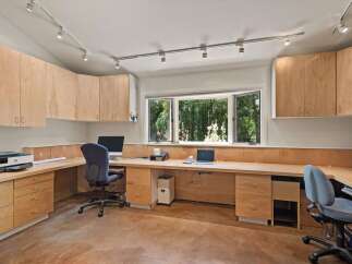 This home office features a spacious L-shaped desk with ample storage, including built-in drawers and overhead cabinets.