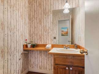 This charming bathroom features a rustic wood-paneled wallpaper that adds warmth and character to the space.