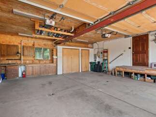 This spacious garage offers ample storage with custom wooden cabinetry lining the walls and a dedicated workbench area.