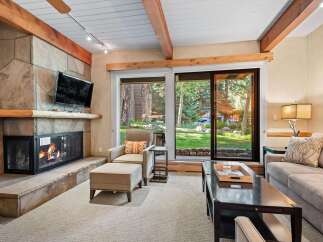 Cozy living room featuring a stone fireplace with a crackling fire and a mounted television.