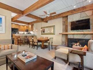 Experience rustic charm and modern comfort in this inviting living space, featuring exposed wooden beams and a grand stone fireplace.