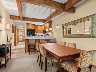 Experience comfortable dining in this inviting space, featuring a rich wooden table surrounded by chairs upholstered in a vibrant, geometric pattern.
