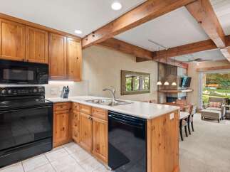 Experience rustic charm in this inviting kitchen featuring warm wooden cabinetry and a sleek black appliance suite, including a built-in microwave and a modern range.