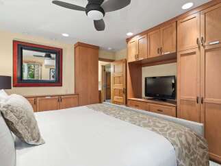 Experience ultimate comfort in this beautifully appointed bedroom, featuring a plush king-sized bed and ample built-in wooden cabinetry for all your storage needs.