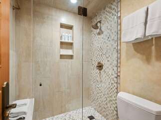 Experience luxury in this beautifully appointed bathroom, featuring a spacious walk-in shower with elegant mosaic tile accents and a convenient built-in niche for toiletries.