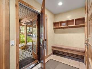 Step into this inviting entryway featuring a charming wooden bench with storage and a convenient coat rack.