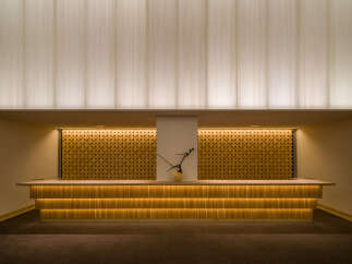 Experience a warm welcome at this hotel's reception area, featuring a beautifully illuminated wooden counter.