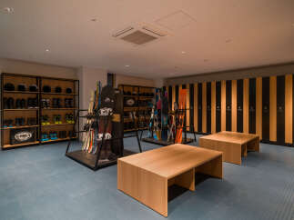 Discover a well-organized ski and snowboard storage area, featuring ample shelving for boots and helmets, alongside dedicated racks for skis and snowboards.