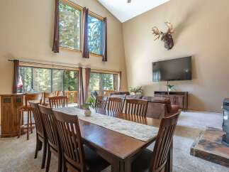 Experience rustic charm in this spacious living and dining area, featuring a vaulted ceiling and large windows that flood the space with natural light.